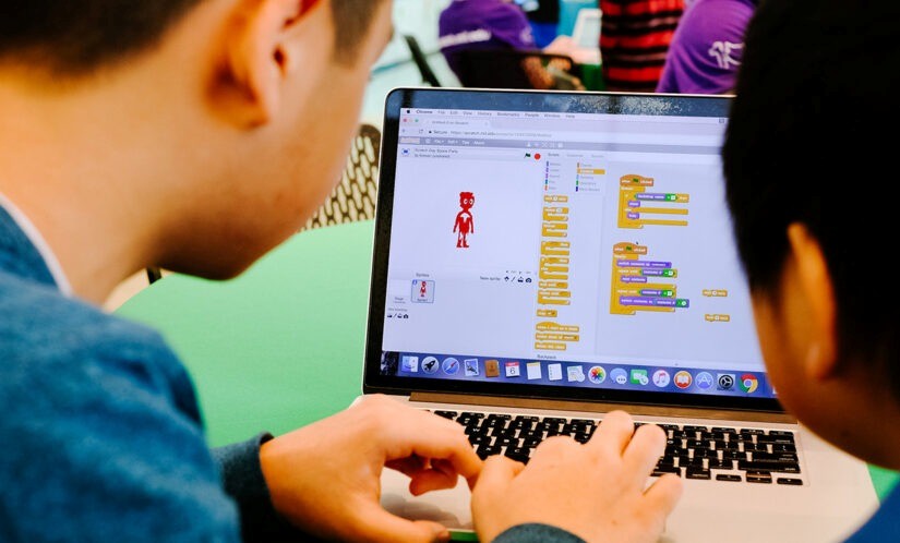 Older child coding on Scratch using colorful block-based commands on a computer screen to create games and animations.