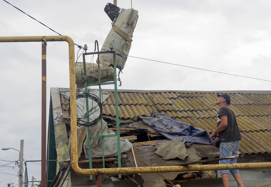 Trabajadores extraen una parte de un misil a través de un agujero en el techo de un edificio alcanzado en un ataque contra el puerto de Odesa, en el sur de Ucrania.