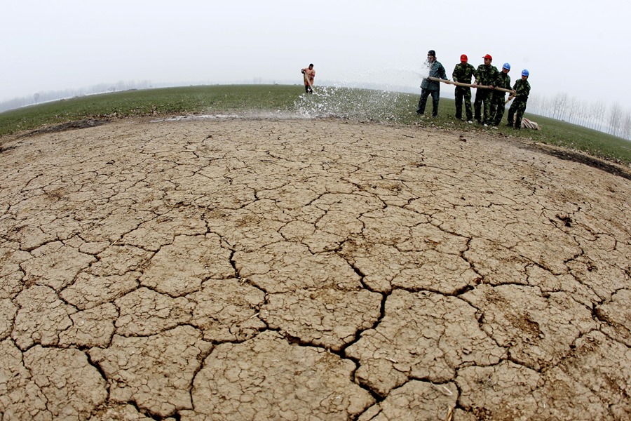Voluntarios de la empresa eléctrica local riegan un campo de trigo seco en Huaibei, China,