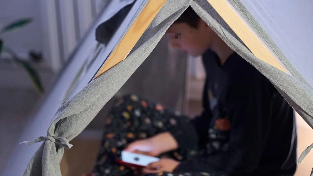 Un niño mira el móvil en su habitación en una foto de archivo EFE/Adrián Ruiz Hierro.
