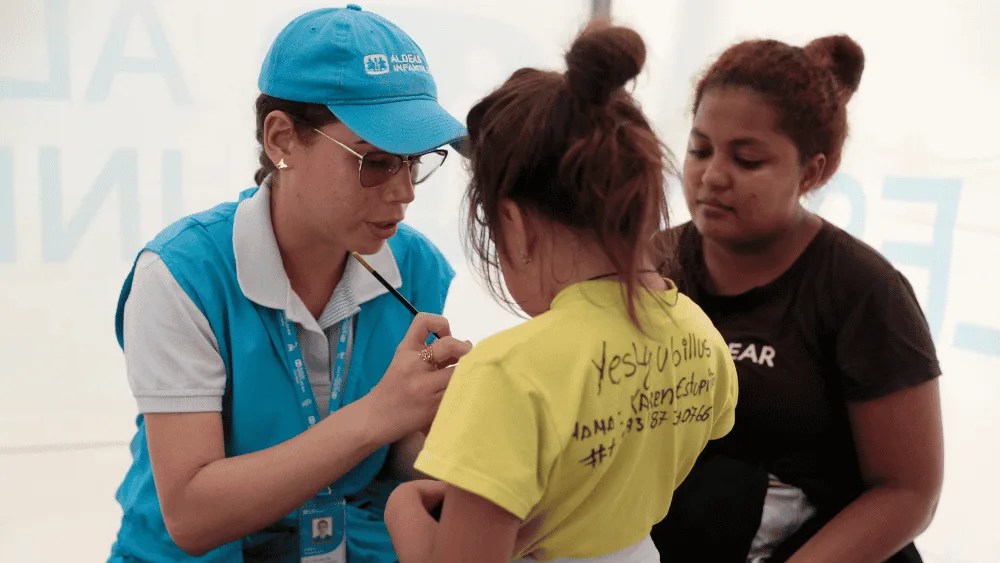 Una funcionaria de Aldeas Infantiles pinta la mano de una niña el 8 de julio de 2024 en Turbo (Colombia).