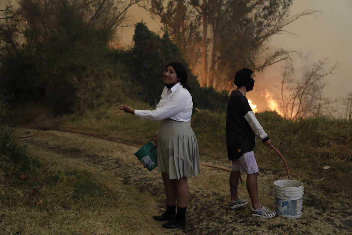 Personas intentan apagar un incendio con baldes de agua en Quito (Ecuador).