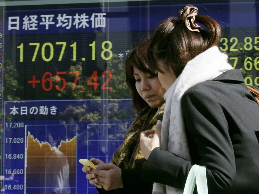Fotografía de archivo de unas mujeres pasando frente a un tablero que muestra el Nikkei este durante la sesión de la Bolsa en Tokio (Japón). Boj EFE/KIMIMASA MAYAMA