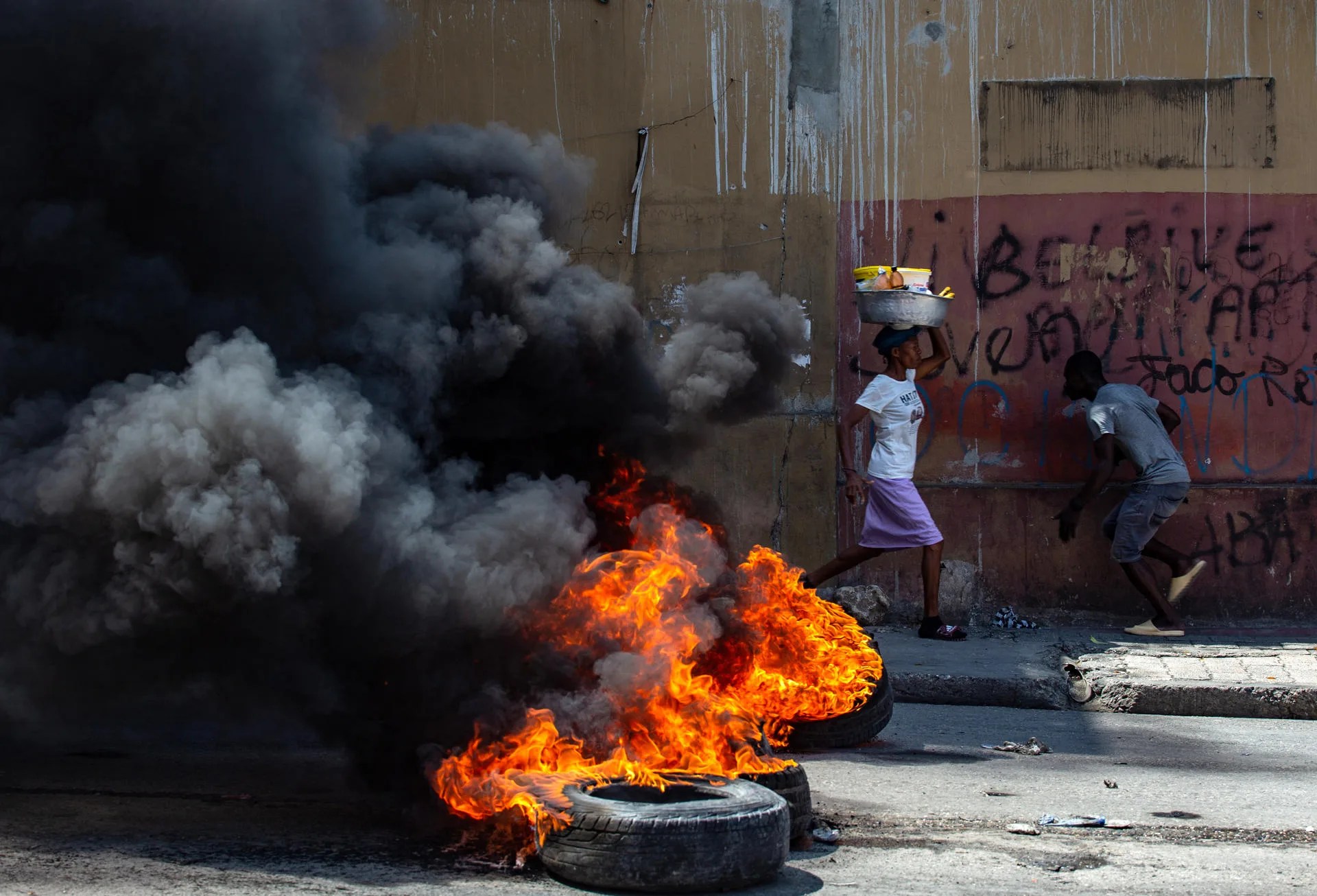 People run past burning tires in Port-au-Prince (Haiti) Mar. 29, 2025. EFE/ Mentor David Lorens