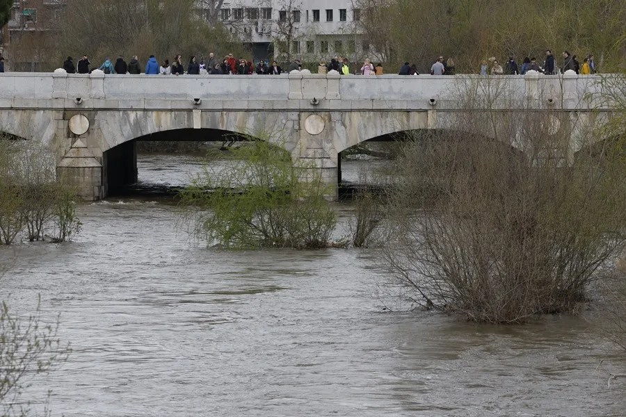 Varias personas observan el caudal del río Manzanares a su paso por Madrid