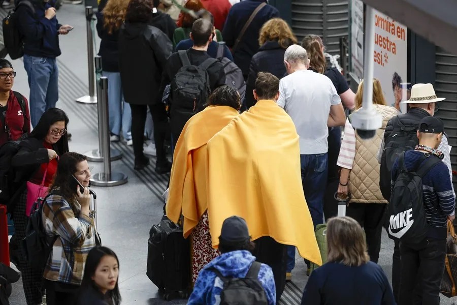 Viajeros de tren afectados por el apagón masivo ocurrido hacia las 12.30 del pasado lunes aguardan en la madrugada de este martes en la Estación de Atocha