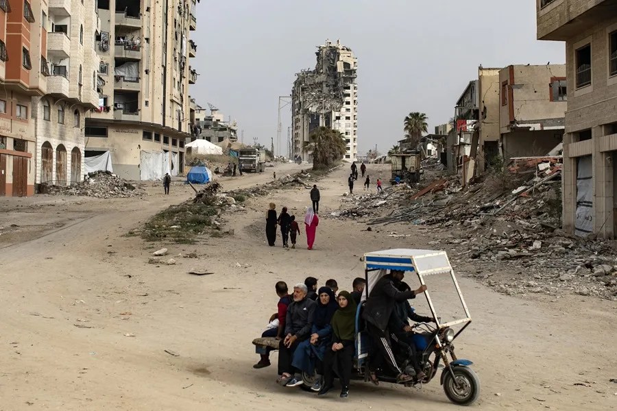 Palestinos desplazados pasan junto a edificios destruidos en el oeste de la ciudad de Gaza