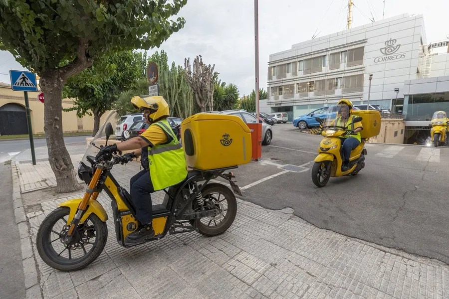 Varios carteros salen de la sede de Correos
