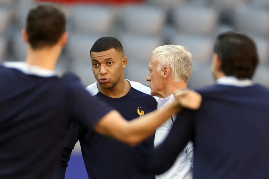 El delantero de la selección de Francia Kylian Mbappé (c-i) conversa con el seleccionador, Didier Deschamps (c-d).