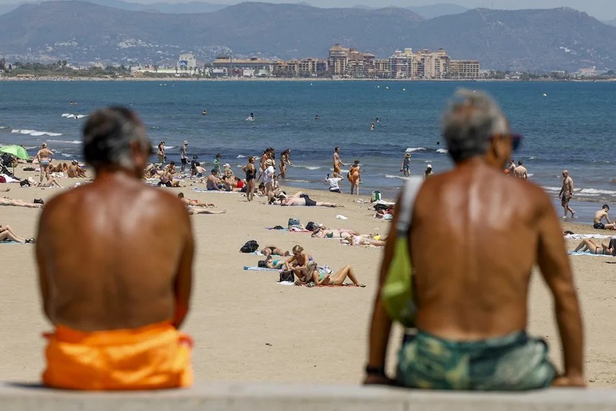 Dos personas contemplan la afluencia en la playa de la Malvarrosa (Valencia).