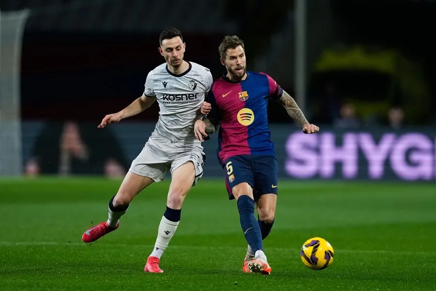 El defensa del F.C. Barcelona Iñigo Martínez (d) disputa un balón con el delantero del Osasuna Raúl García