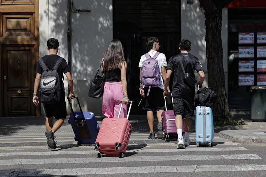 Un grupo de jóvenes acarrea sus maletas por una calle de València.