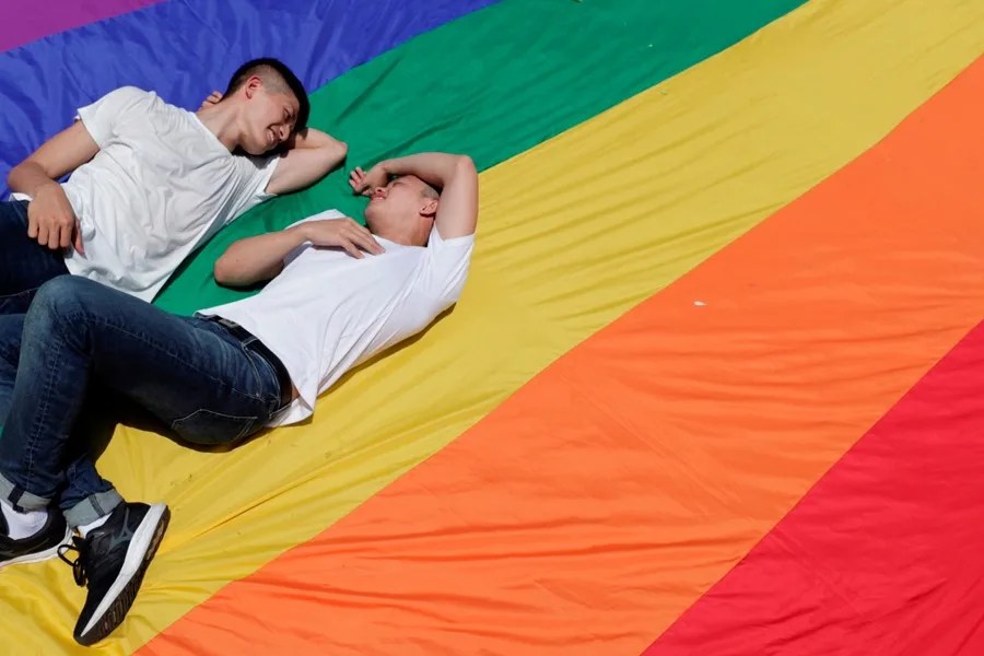 Una pareja se sienta sobre una bandera LGBTI