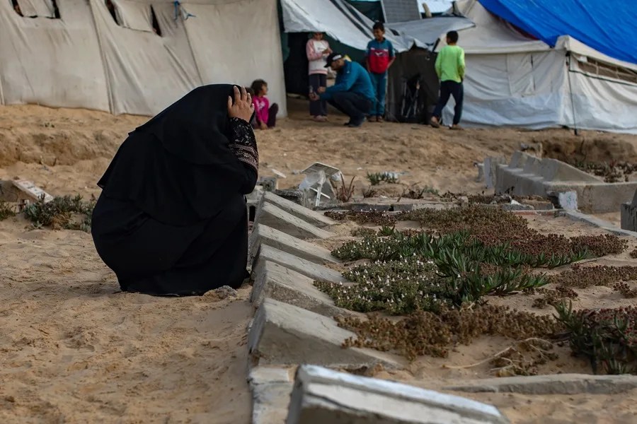 Familias palestinas visitan las tumbas de sus familiares en un cementerio el primer día del Eid al-Adha, en Khan Yunis