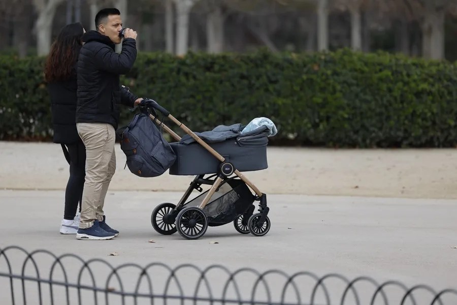 Una pareja pasea con un carrito de bebé en el parque de El Retiro en Madrid.
