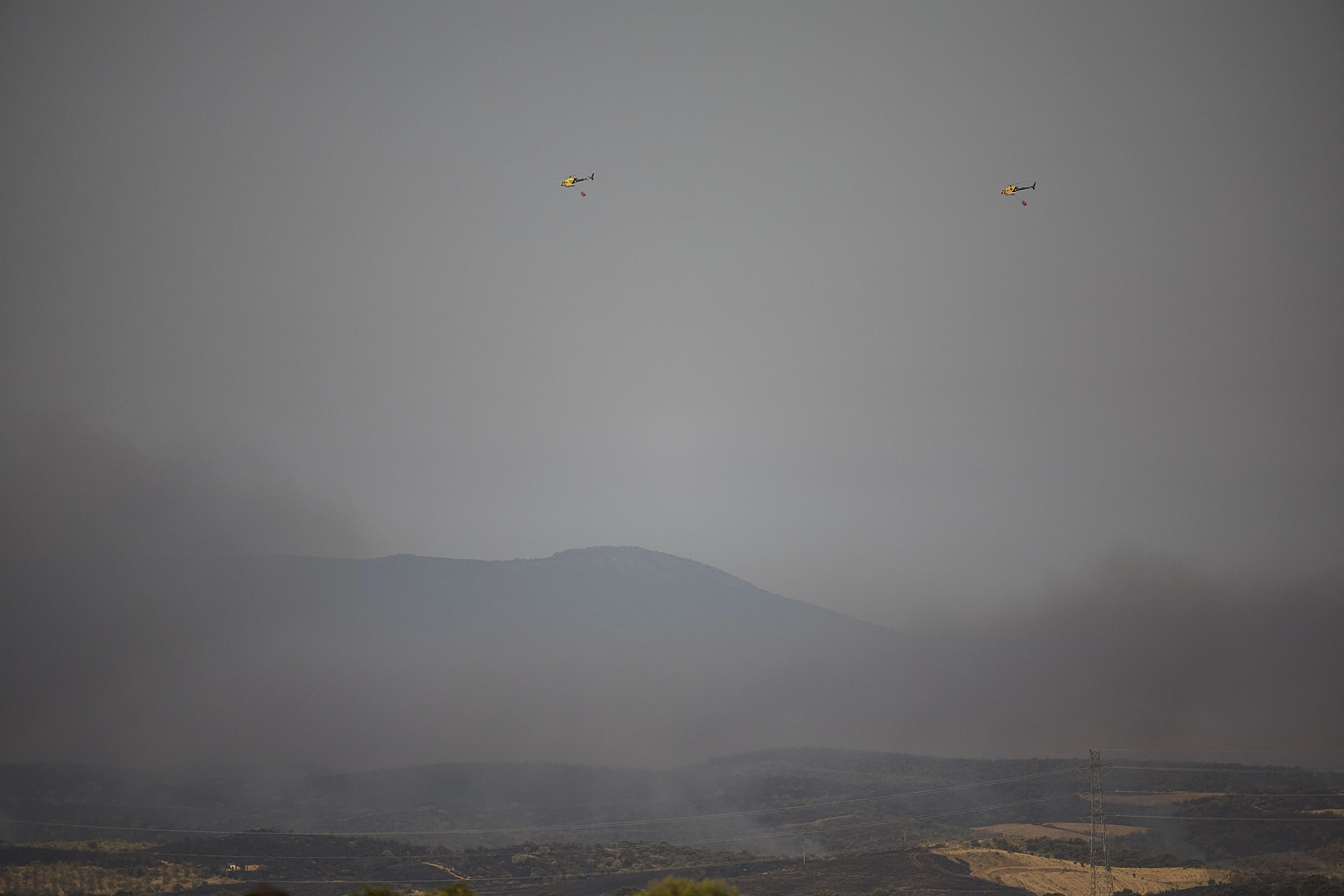 Varios helicópteros trabajan este martes en la extinción del incendio de Navalmoralejo (Toledo), activo en Extremadura y Castilla-La Mancha. EFE/ Manu Reino