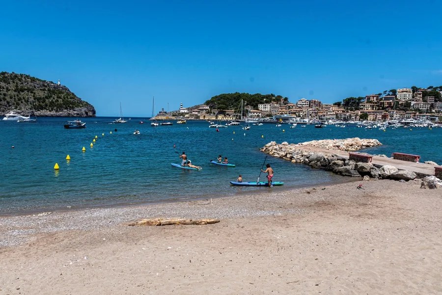 Varias persona realizan deporte acuáticos en la playa de Sóller.
