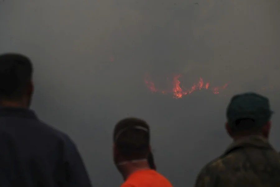 Vecinos esperan órdenes de La UME para bajar a refrescar una zona incendiada.