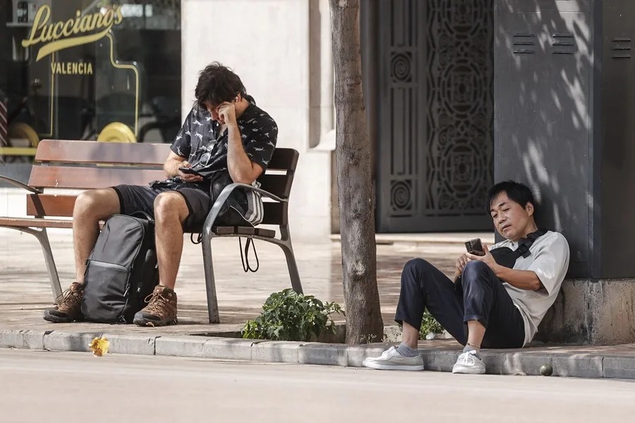 Dos hombres se toman un respiro a la sombra, este lunes 18 de agost