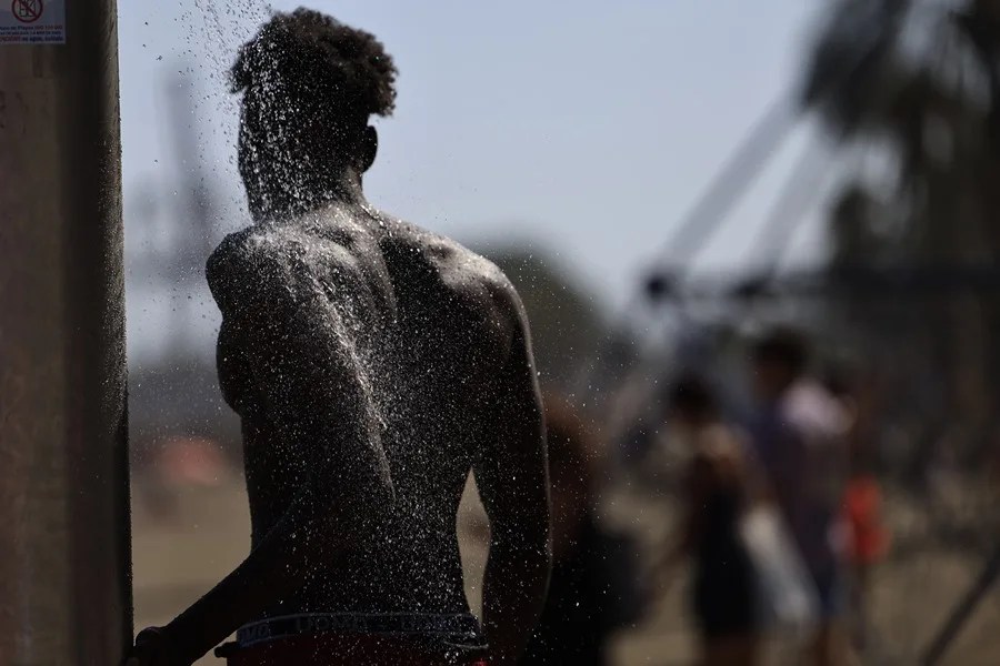 Una persona se refresca en la playa de la Malagueta