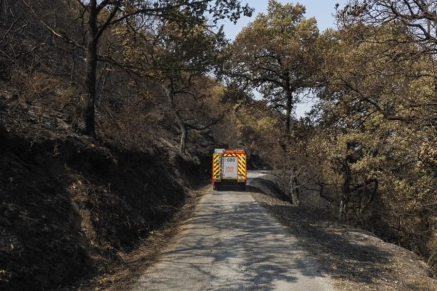 Un vehículo de extinción de incendios avanza por una zona quemada cerca de la localidad de Quiroga, en Lugo