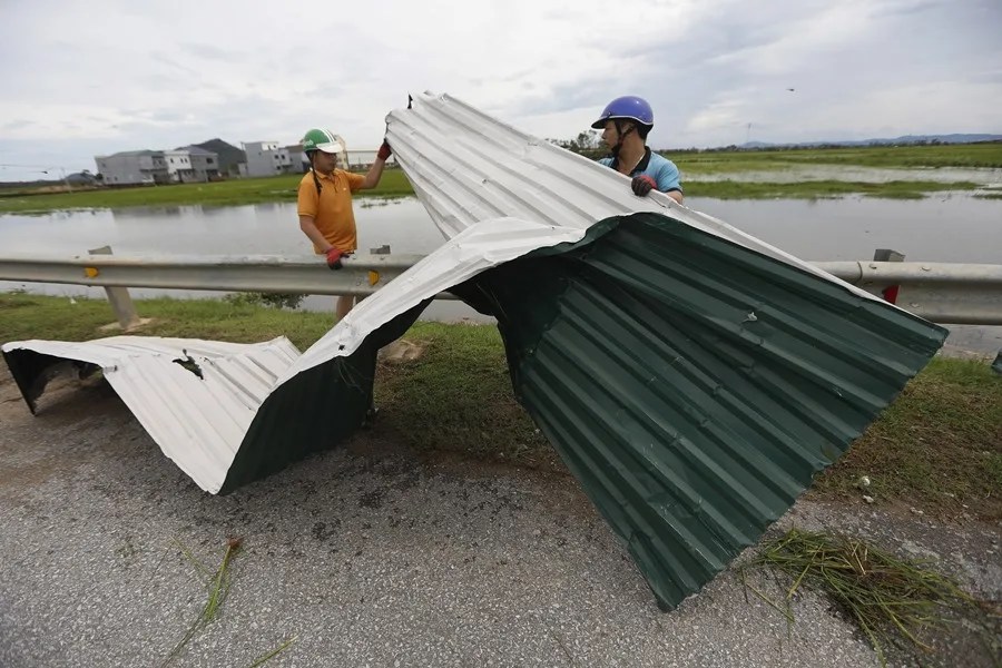 Personas limpian planchas de hierro que el tifón Kajiki arrojó sobre una carretera en Nghi Xuan, provincia de Ha Tinh, Vietnam
