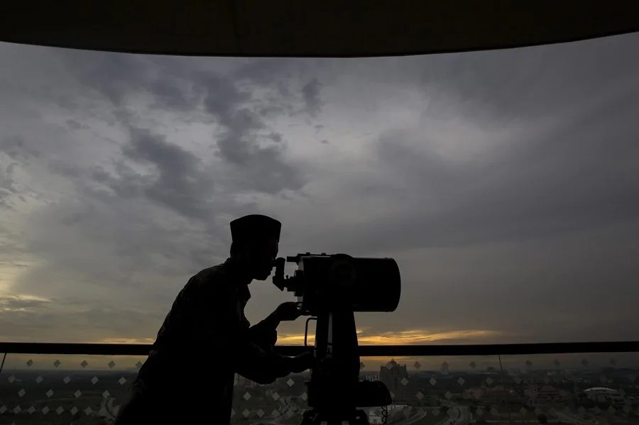 Un hombre mira a través de un telescopio.