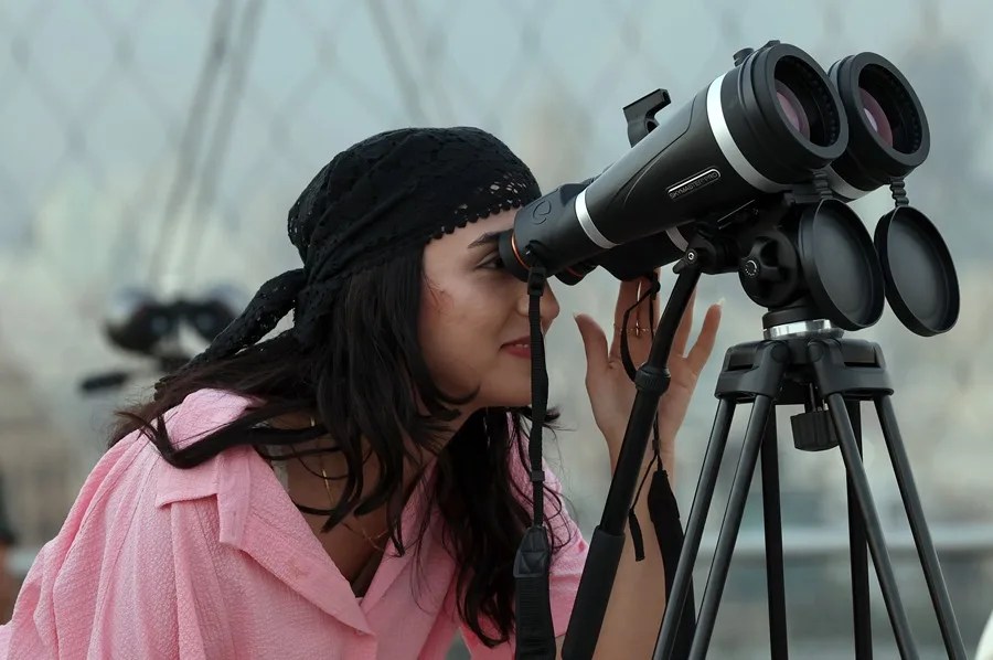 Una mujer mira a través de un telescopio.