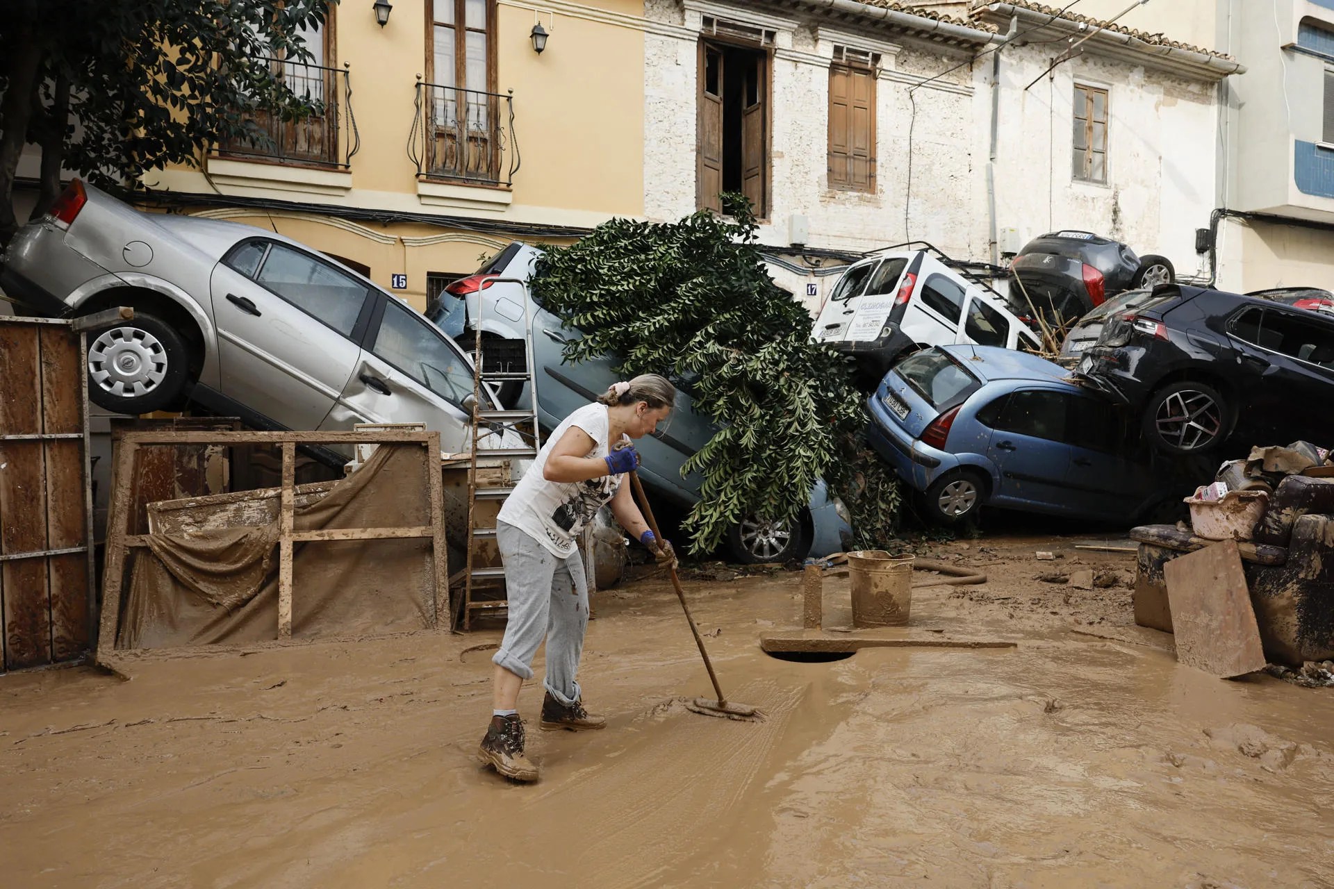 Una vecina de Paiporta limpia el lodo de una calle afectada, poco después de la dana. EFE/Biel Aliño
