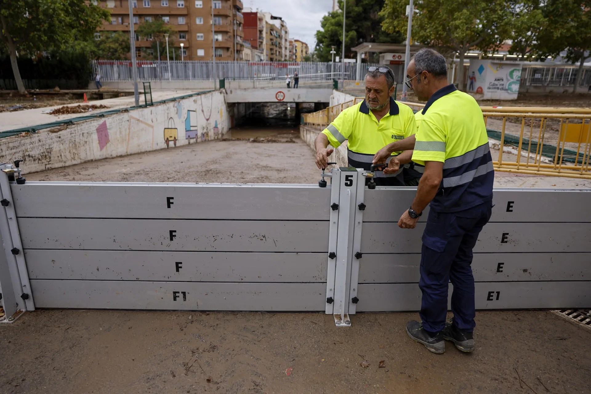 Operarios colocan barreras antinundación en el barranco de la Saleta en Aldaia, Valencia, este lunes. La madrugada ha transcurrido con "normalidad" y sin "incidencias destacadas" en municipios de la provincia de Valencia afectados por la dana del pasado 29 de octubre, aunque las precipitaciones registradas han provocado el desbordamiento del barranco de La Saleta en Aldaia, la "subida puntual" del barranco del Poyo en Paiporta o el desprendimiento de piedras en una carretera en Buñol. EFE/ Biel Aliño
