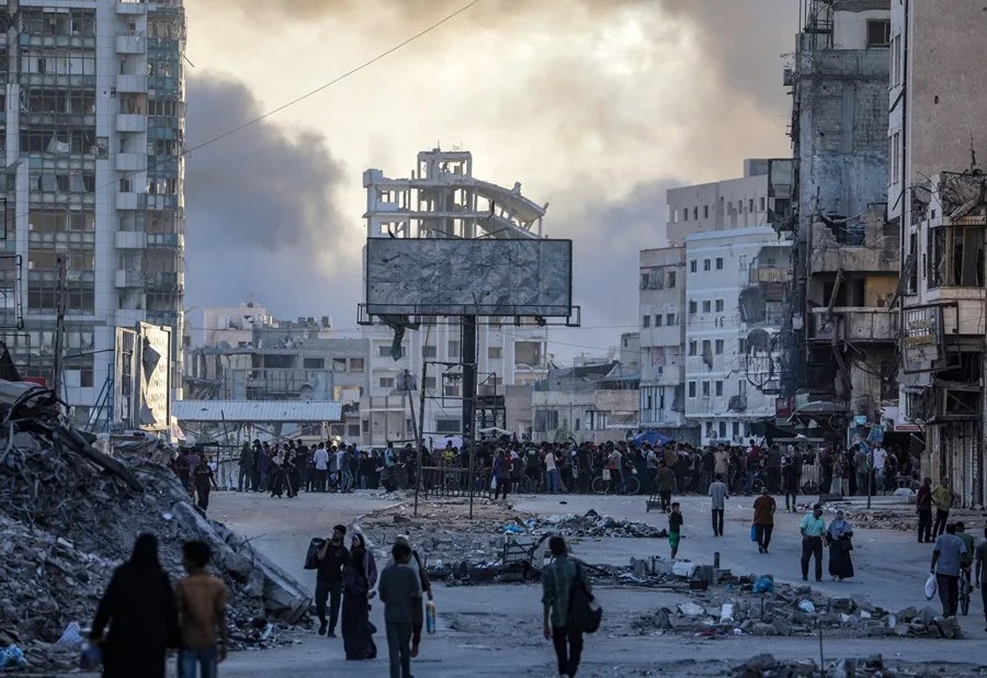 Palestinos se movilizan en la plaza Al Saraya mientras se eleva el humo tras un ataque aéreo israelí en el barrio de Tal Al Hawa durante una operación militar israelí en la ciudad de Gaza
