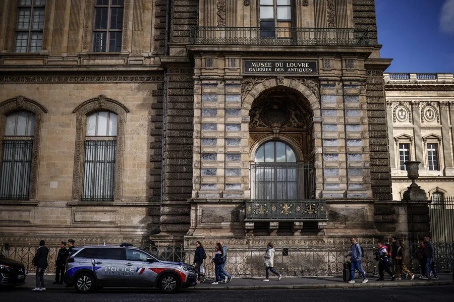 Policías franceses observan una ventana rota un día después de un robo en el Museo del Louvre en París, Francia