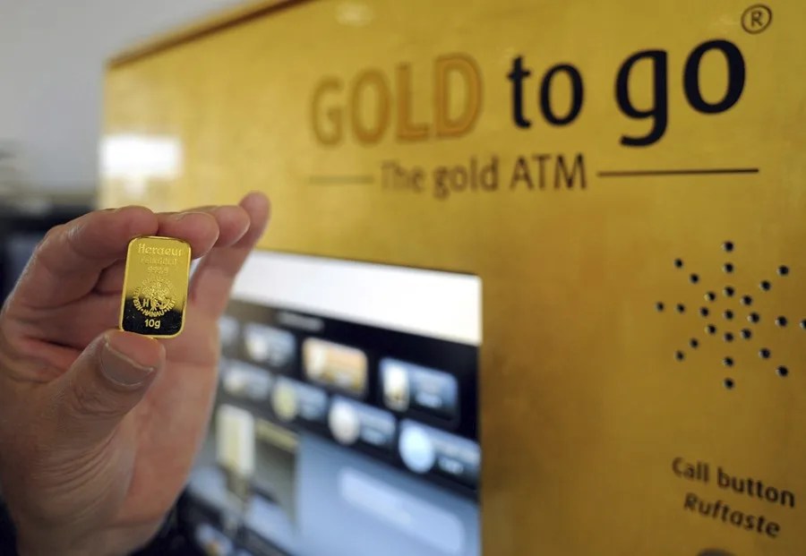 Un hombre sostiene una barra de oro de 10 gramos, despúes de la demostración de cómo se usa la máquina de venta de oro ("Gold to go" en inglés)