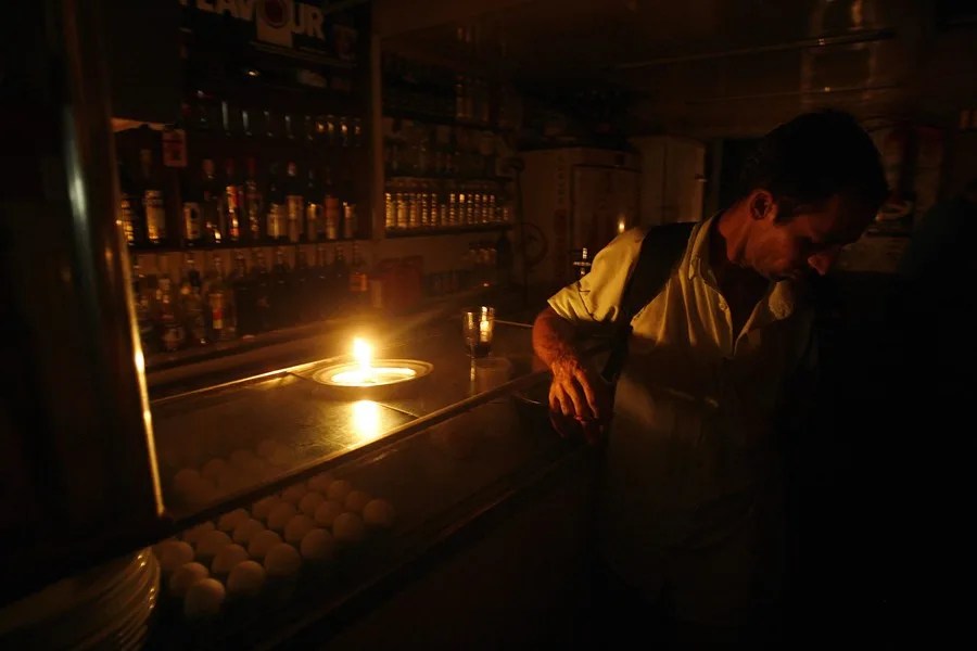 Un cliente asiste a un bar a oscuras en Río de Janeiro por un corte de energía.