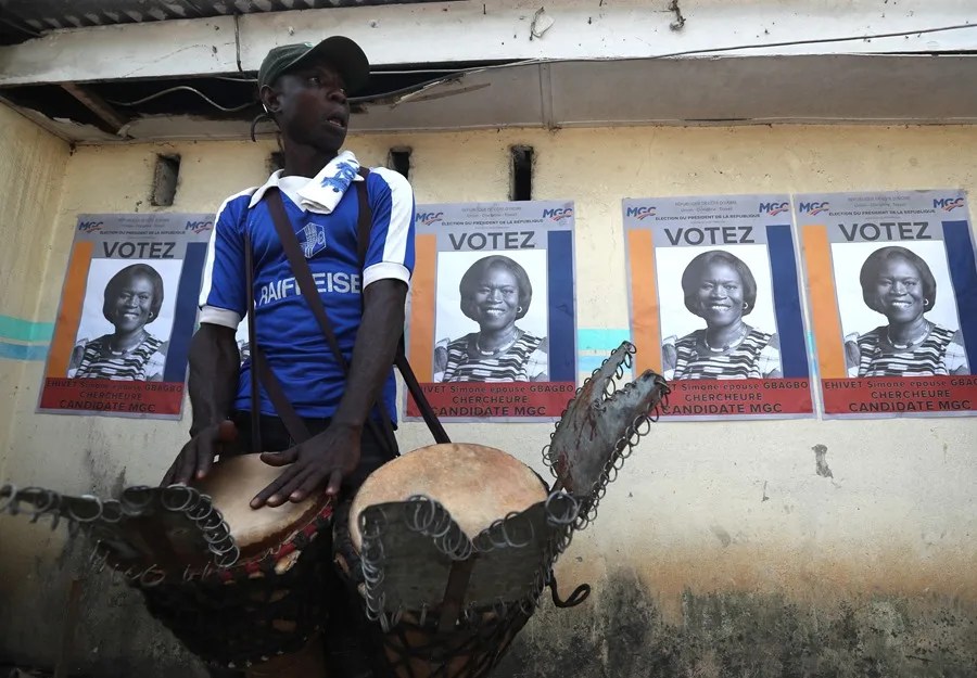 Un simpatizante toca tambores junto a carteles de la ex primera dama de Costa de Marfil, Simone Ehivet Gbagbo, candidata presidencial del Movimiento de Generaciones Capaces (MGC), durante un mitin en Abiyán