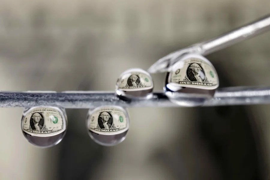 Billetes de un dólar reflejados en gotas de agua en San José (Costa Rica).