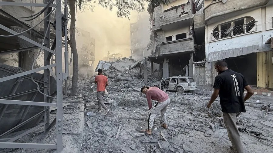 Varios hombres caminan por los escombros tras uno de los ataques lanzados este domingo por Israel en Gaza.