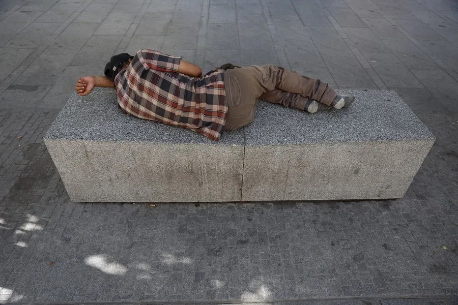 Un sintecho duerme sobre un banco