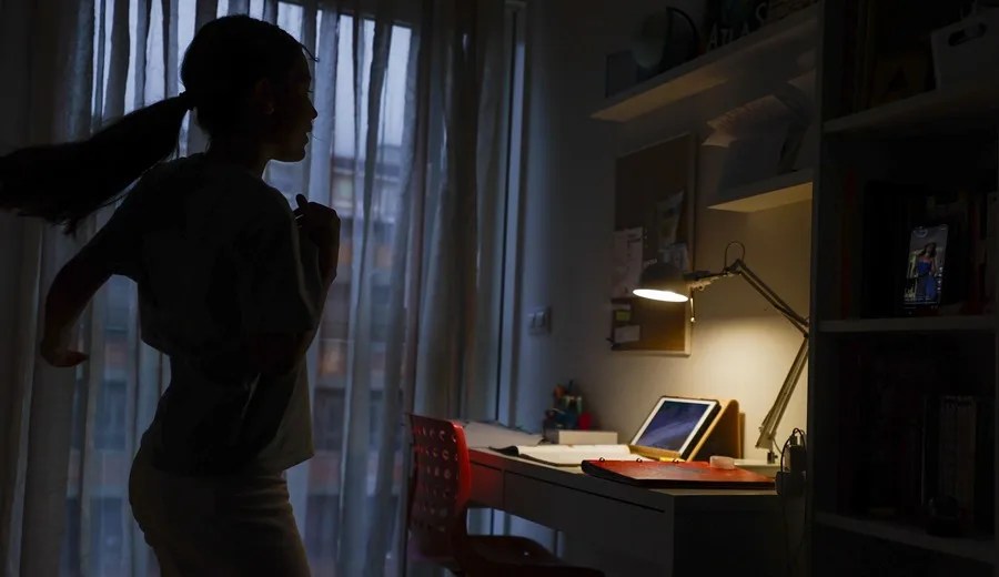 Una adolescente baila un TikTok junto a su teléfono móvil.