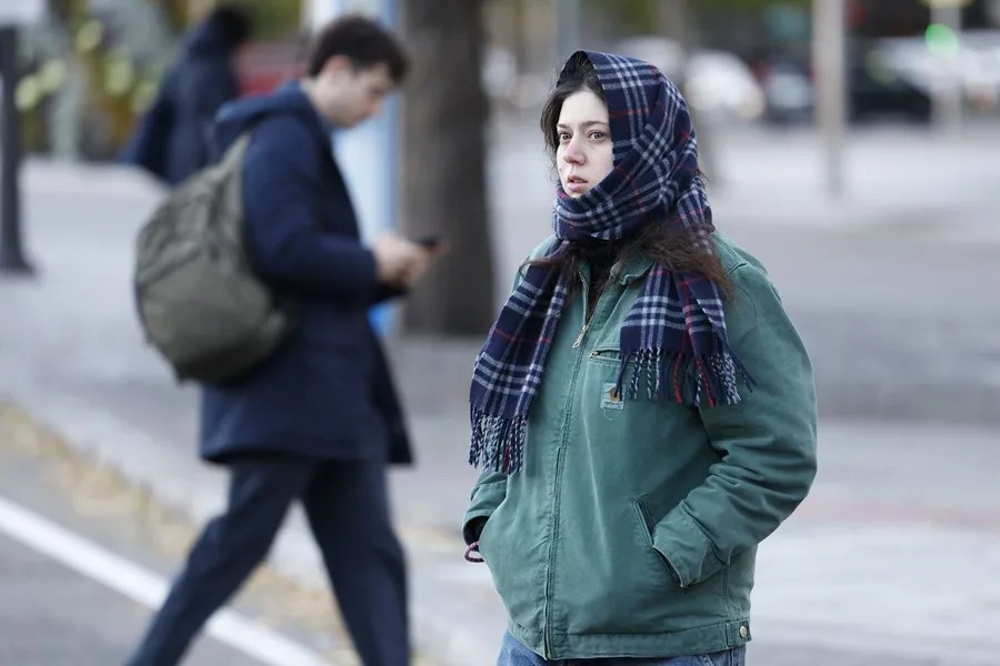 Una mujer se protege del frío mientras camina por Madrid