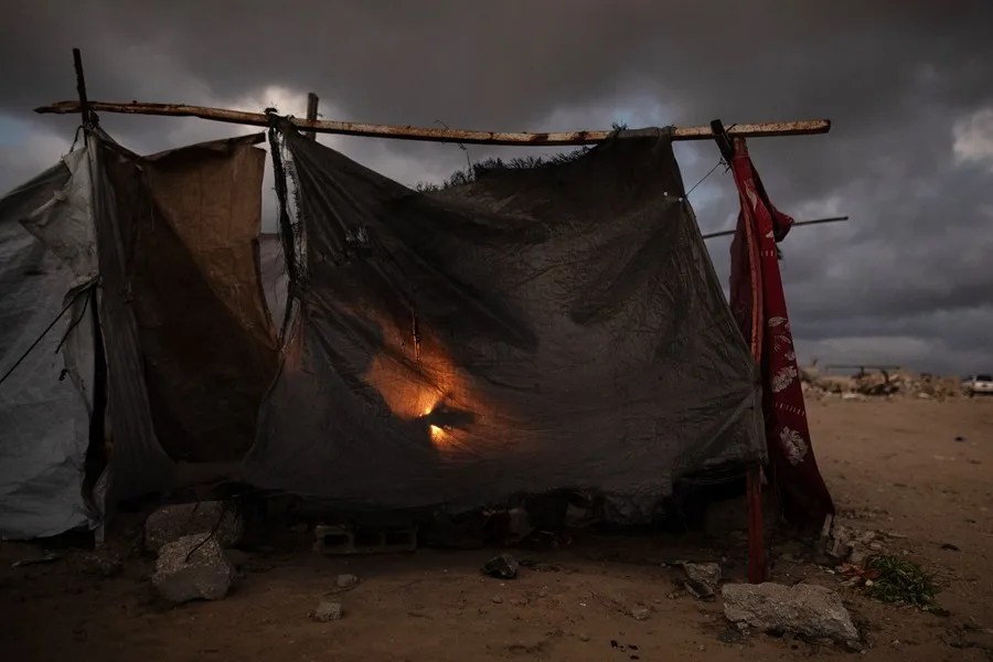 Miembros de una familia palestina desplazada se calientan junto a una fogata frente a su refugio en la ciudad de Khan Younis