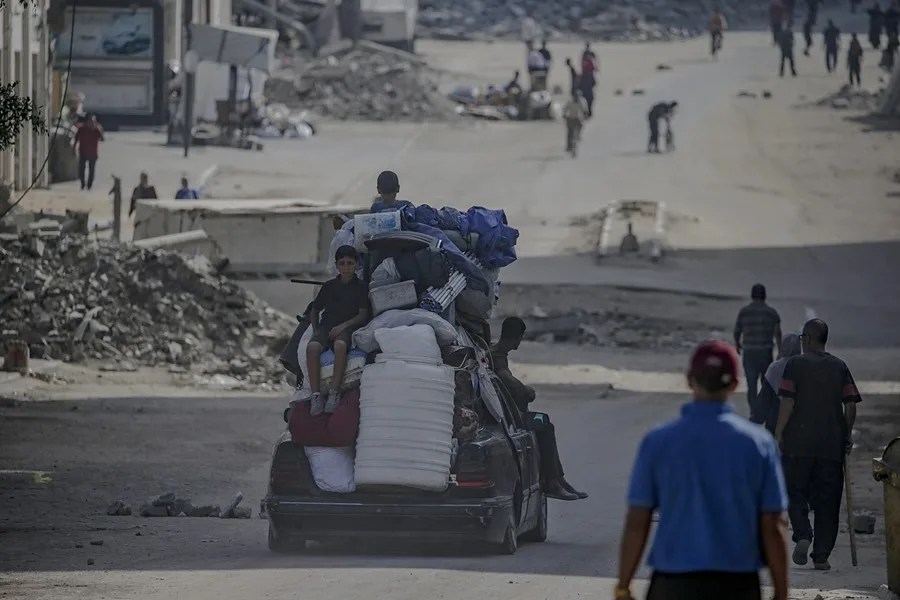 Palestinos desplazados internos se desplazan con sus pertenencias antes de un ataque aéreo israelí en la ciudad de Gaza