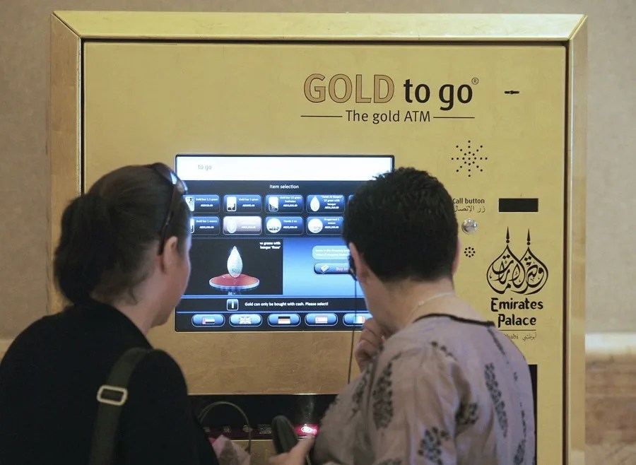Dos mujeres frente a un cajero automático de oro