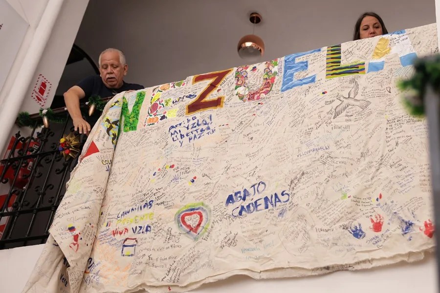 Personas cuelgan un cartel este sábado, en el Centro Venezolano Argentino en Buenos Aires (Argentina).