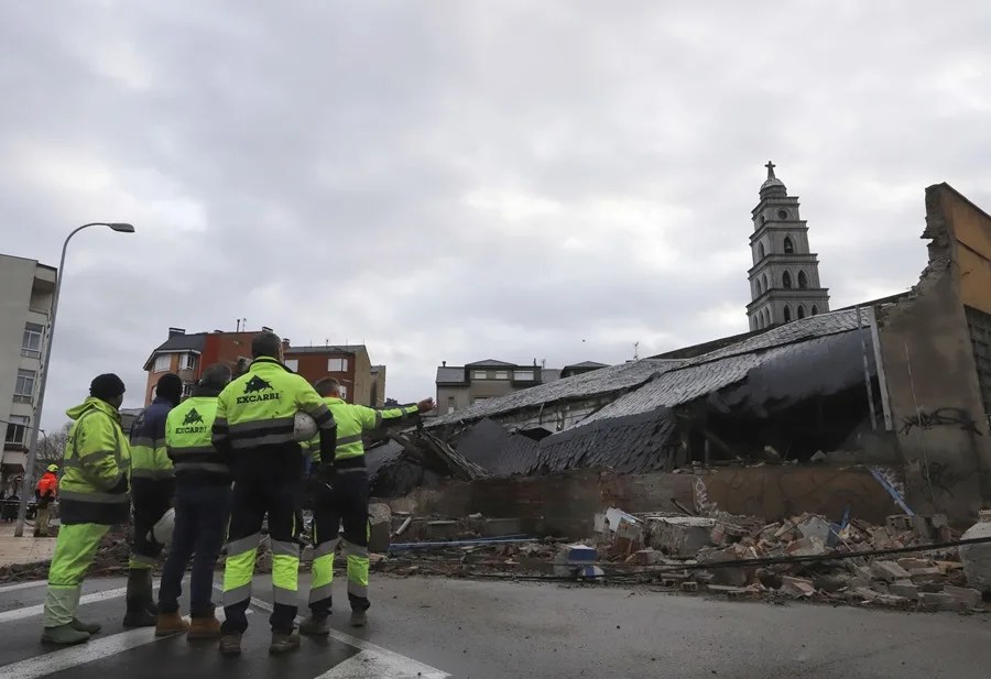 Varios trabajadores de la construcción observan un edificio derrumbado en la ciudad de Ponferrada