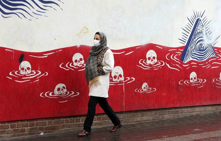 Una mujer iraní pasa junto a un mural antiestadounidense en una calle de Teherán, Irán
