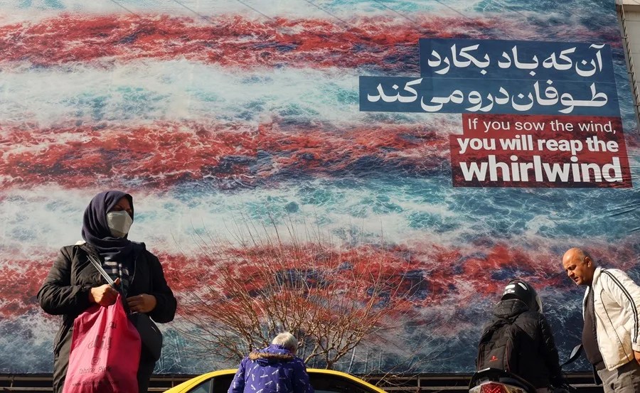 Iraníes caminan cerca de un enorme cartel antiestadounidense colgado en la plaza Enqelab de Teherán,