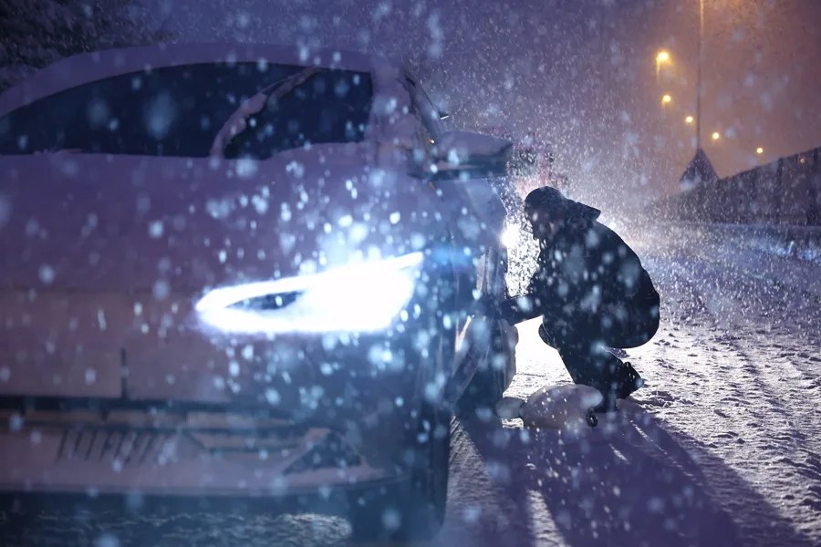 Un hombre se coloca cadenas para la nieve durante una nevada