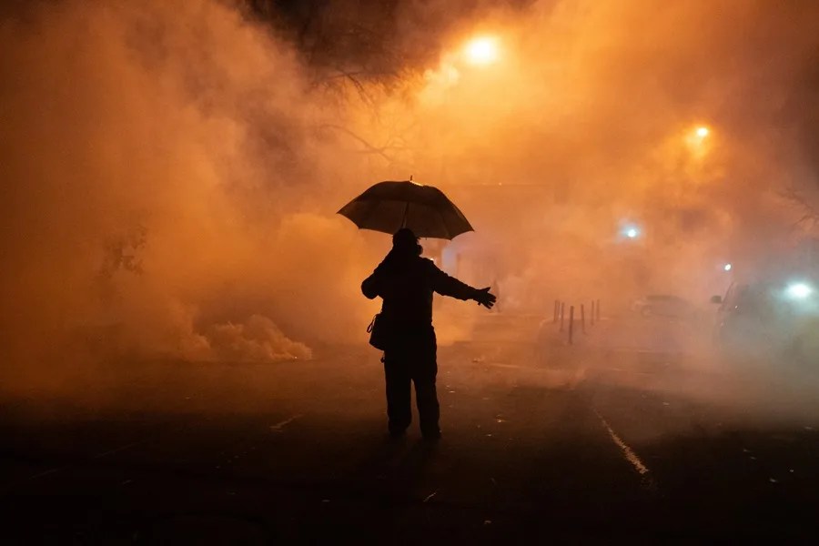 Una persona camina a través de una nube de gas lacrimógeno lanzado por agentes federales durante una protesta en Minneapolis, Minnesota.