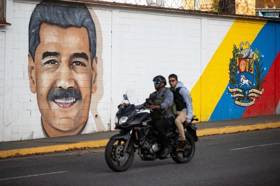 Personas transitan frente a un mural del presidente de Venezuela, Nicolás Maduro